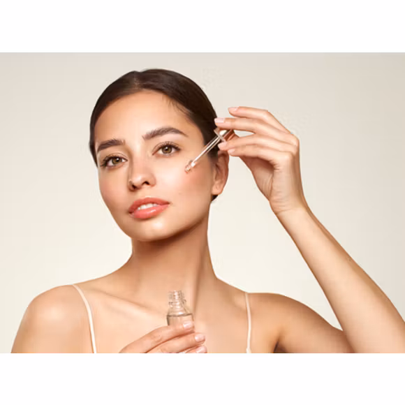 Kobieta nakładająca pipetą kosmetyk na twarz