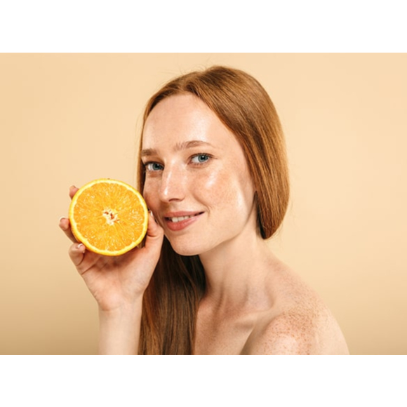 Rudowłosa dziewczyna bez makijażu trzymająca pomarańczę - tytułowa.