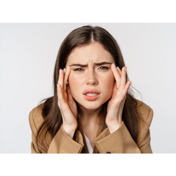 Kobieta, która dotyka swoich skroni marszcząc brwi - zdjęcie