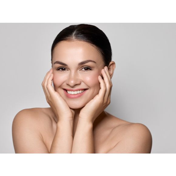 Uśmiechnięta kobieta trzymająca swoją twarz w dłoniach - zdjęcie