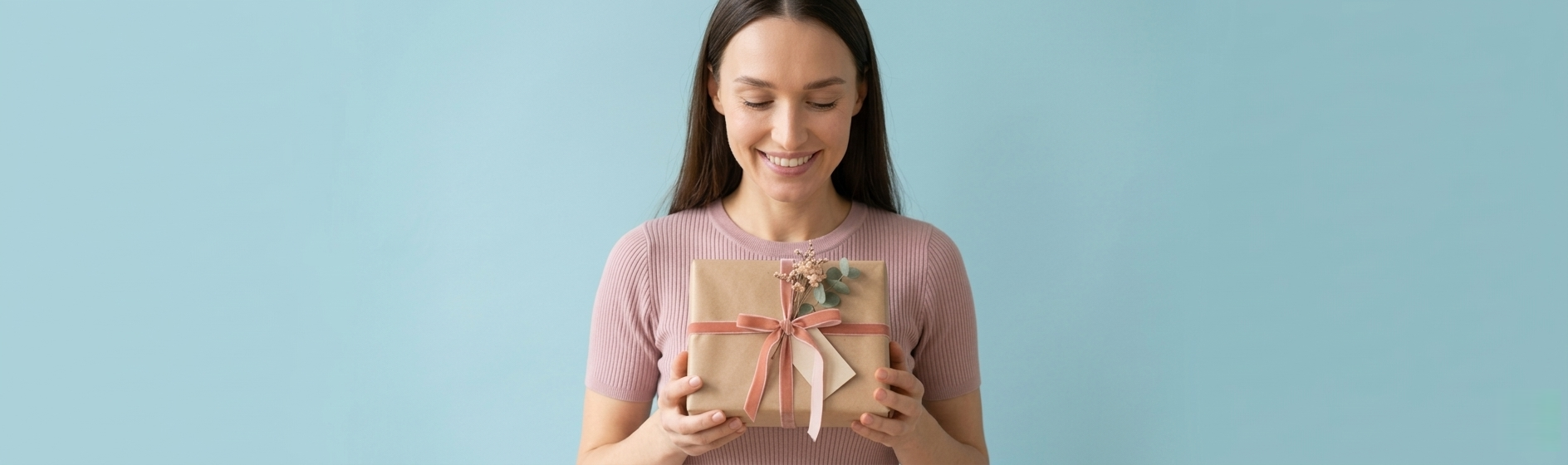 Uśmiechnięta kobieta z podarunkiem. Jaki prezent na Dzień Kobiet wybrać? Zestaw kosmetyków tołpa.® dla żony, mamy lub siostry.