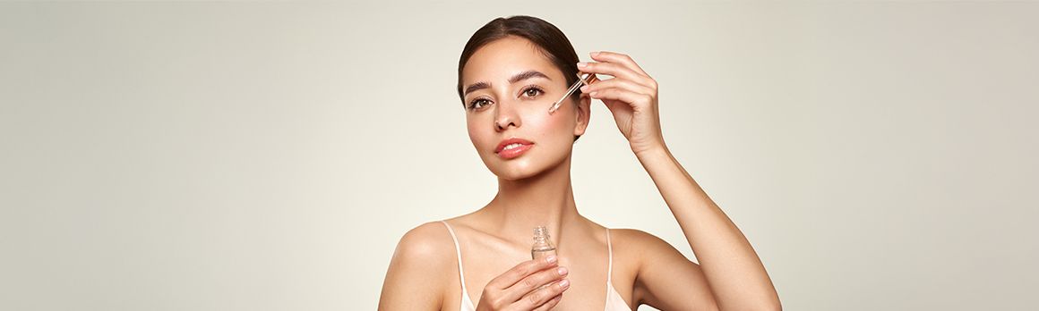 Kobieta nakładająca pipetą kosmetyk na twarz