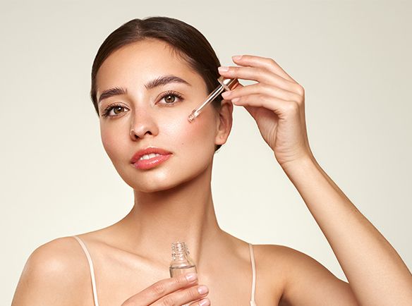 Kobieta nakładająca pipetą kosmetyk na twarz