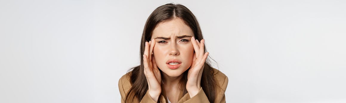 Kobieta, która dotyka swoich skroni marszcząc brwi - zdjęcie