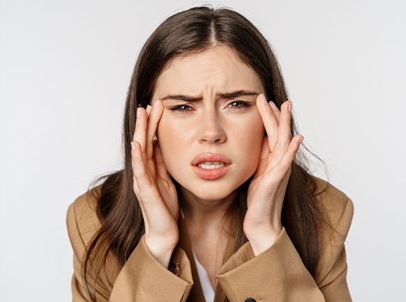 Kobieta, która dotyka swoich skroni marszcząc brwi - zdjęcie