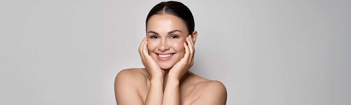 Uśmiechnięta kobieta trzymająca swoją twarz w dłoniach - zdjęcie