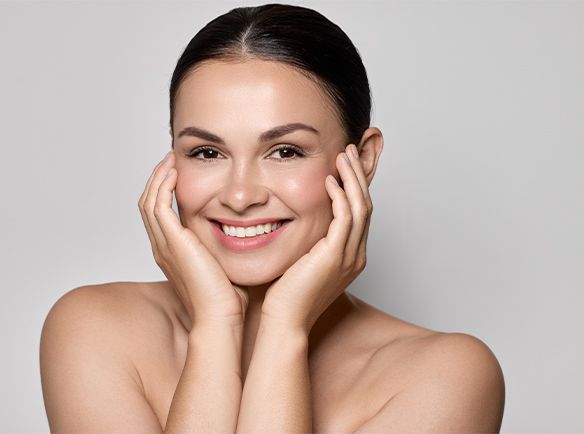 Uśmiechnięta kobieta trzymająca swoją twarz w dłoniach - zdjęcie