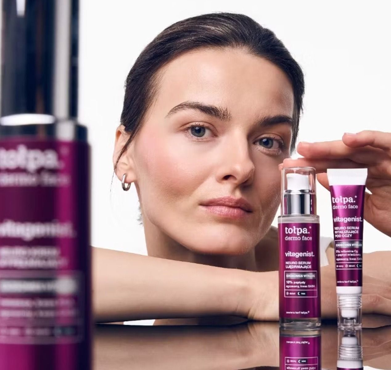 Kobieta trzymająca dłoń na kosmetykach z lini tołpa.® dermo face vitagenist. - zdjęcie