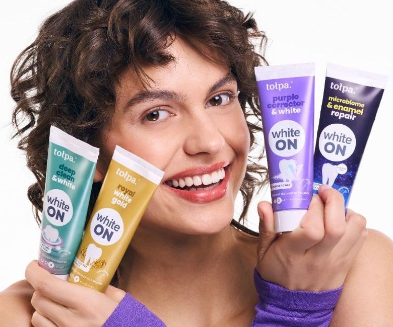 usmiechnięta kobieta z tubkami past do zębów