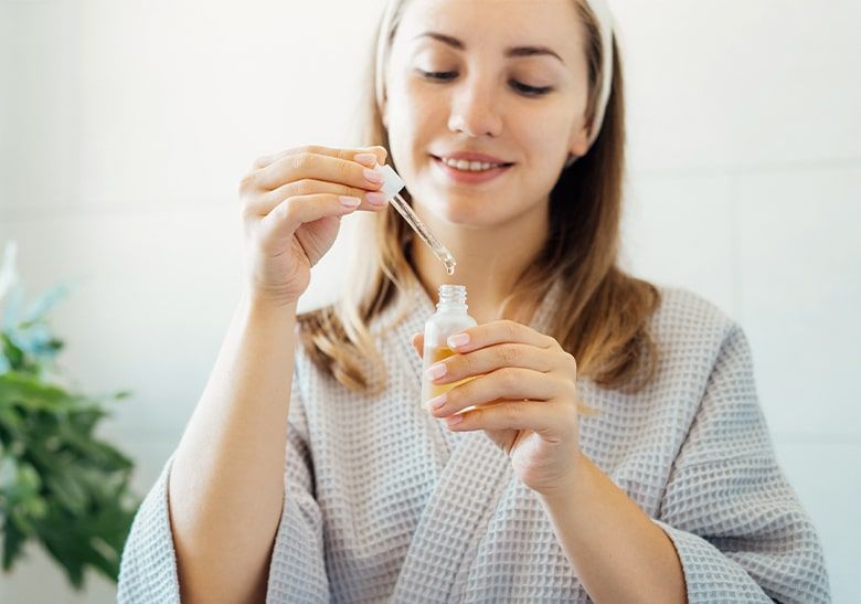 Kobieta nabierająca serum pipetą z buteleczki - zdjęcie.